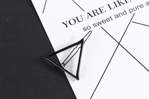 Detail of a geometric black metal triangle hair clip with minimalist matte finish