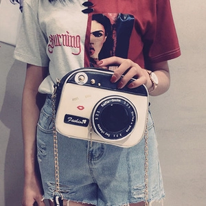 Detail of camera-shaped PU crossbody bag with white and black panels and gold chain strap