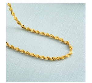 Detailed macro view of a gold-plated twisted facet chain necklace with high metallic luster