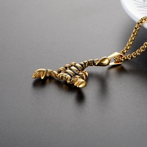 Polished gold stainless steel scorpion pendant necklace on dark textured surface