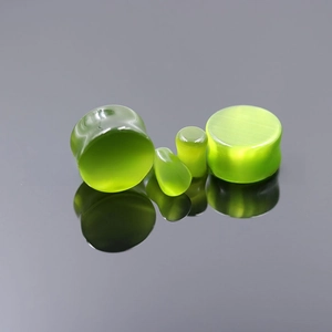 Macro detail of emerald green cat eye stone ear plugs with smooth polished surface finish