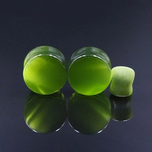 Detail of green cat eye stone ear plugs with smooth surface and reflective finish