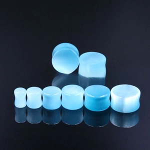 Macro view of light blue cat eye stone ear plugs showing gradient sizing and saddle shape