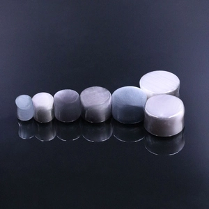 Macro display of cat eye stone ear plugs showing a range of sizes on dark surface