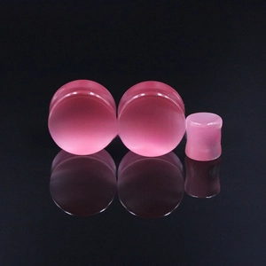 Detailed macro view of pink cat's eye stone ear plugs with smooth reflective surface