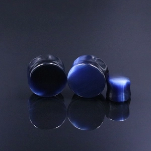 Macro detail of dark blue cat eye stone ear plugs in three various sizes with reflections