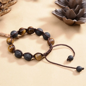 Adjustable woven bracelet with 12mm tiger eye and volcanic lava stone beads on beige texture