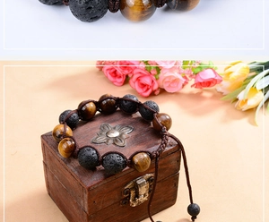 Macro detail of hand-woven bracelet with 12mm tiger eye and volcanic lava stones