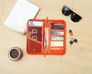Top view of an orange travel passport wallet with multiple card slots on a wooden floor