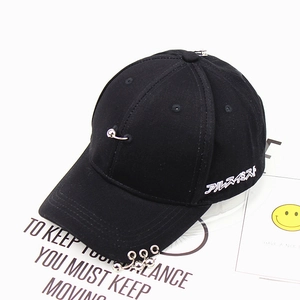 Detail of black baseball cap with metal rings, silver pin and white Japanese embroidery