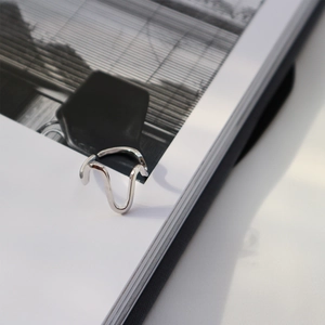 Artistic close-up of wavy S925 sterling silver ring resting on an open book