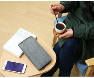 Close-up of a dark grey travel organizer bag on a wooden table with lifestyle accessories