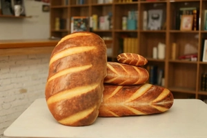 Realistic bread plush pillows in baguette and round shapes on a cozy white desk
