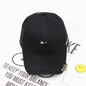 Detail of black cotton baseball cap with silver safety pin and metal rings decorations