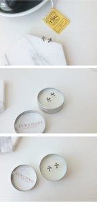 Detail view of silver cross stud earrings displayed on a marble tray and metal tin