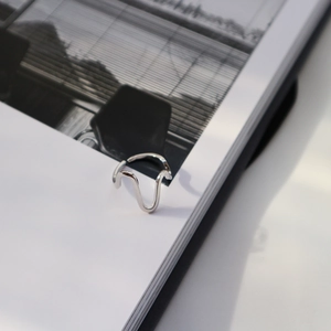 Detailed view of the wavy S925 sterling silver ring showing curved lines on a book page