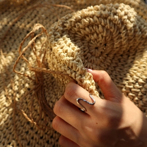 Macro detail of a minimalist S925 sterling silver ring with a twisted wave design
