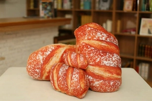 Detailed view of realistic 3D bread plush pillows in various sizes on a white table