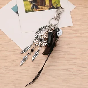 Detail of dream catcher keychain with yin yang charm, black feathers and crystal on wood