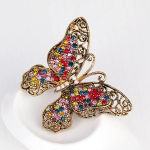 Vintage gold butterfly brooch set with colorful rhinestones on a white background