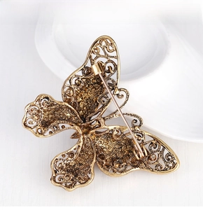 Macro shot of antique gold butterfly brooch with intricate filigree details and pin back
