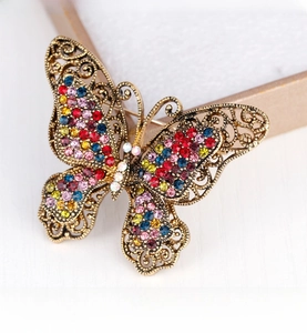 Macro detail of vintage butterfly brooch featuring colorful rhinestones and gold filigree