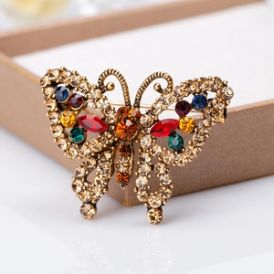 Vintage butterfly brooch in antique bronze with colorful rhinestones on a beige jewelry box