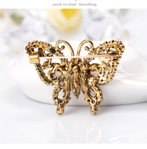 Golden vintage butterfly brooch with sparkling rhinestones on a white reflective surface