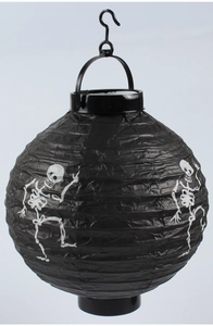 Detail of a black Halloween paper lantern featuring a white skull print and plastic handle