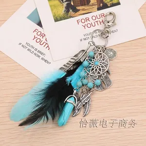 Close-up of dreamcatcher keychain with feathers and hexagonal stone on wood background