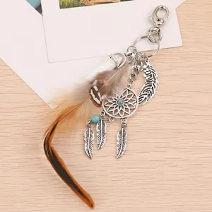 Silver dreamcatcher keychain with blue opal bead and natural feathers on wood background