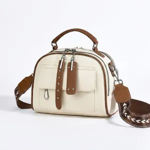Close-up of beige PU leather tote featuring brown handles and patterned woven shoulder strap