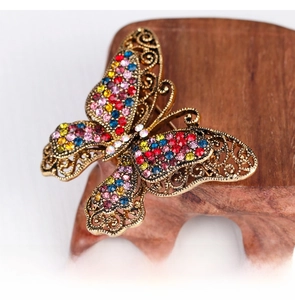 Macro detail of vintage butterfly brooch with colorful crystals on a wooden base
