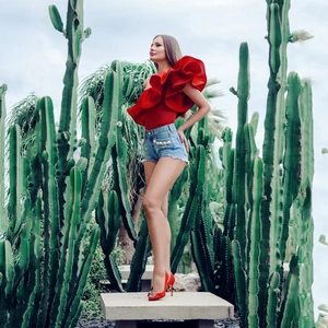 Dettaglio top rosso con volant monospalla e pantaloncini denim con perle