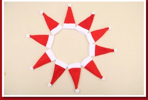 Radial arrangement of ten mini red velvet Christmas hats with white pom poms for cutlery