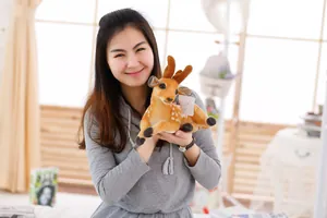 Detail eines Sika-Hirsch-Plüschtiers mit weißen Flecken, gehalten von einem Modell