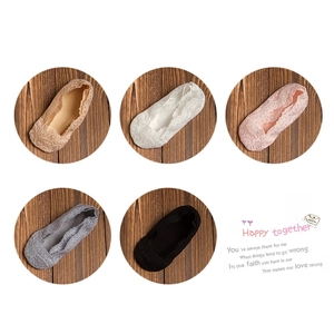 Fünf Paar unsichtbare Mädchen-Spitzensocken in verschiedenen Farben auf dunklem Holz