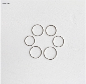 Macro view of six minimalist S925 sterling silver thin rings on a white wood texture