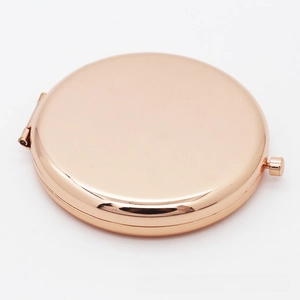 Polished rose gold round makeup mirror in closed state with push-button clasp