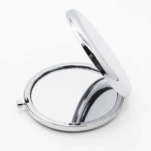 Close-up of a silver-plated circular compact makeup mirror showing dual-sided glass and metal latch