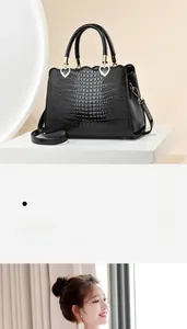Détail du sac à main noir texture croco avec cœur doré et bandoulière ajustable
