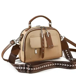 Detail of cream crossbody bag with brown woven strap and metallic zipper accents