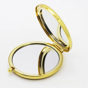 Detailed view of golden double-sided folding makeup mirror with push-button clasp