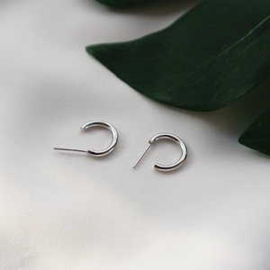 Detailed view of 925 sterling silver geometric C-shape stud earrings on white fabric