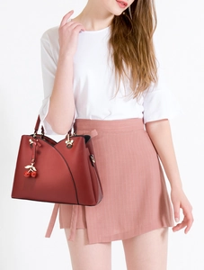 Close-up of deep red lychee grain leather handbag with golden hardware and cherry charm