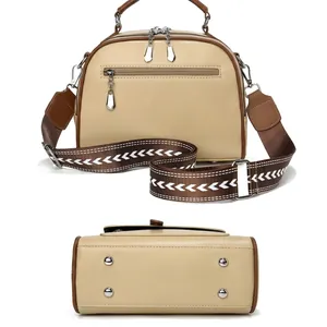 Back view of beige crossbody bag with brown handles and patterned shoulder strap