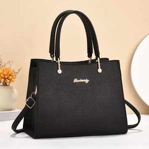 Detail of black lychee grain leather handbag featuring gold logo and hardware
