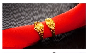 Detailed close-up of golden floral and sunburst embossed rings on a vibrant red backdrop
