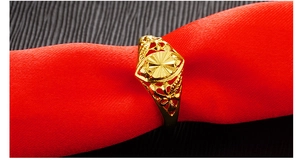 Detail of gold-plated ring with hollow patterns on red fabric background