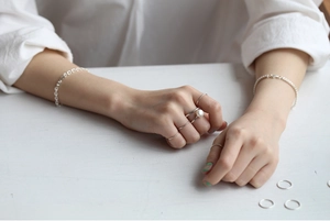 Close-up of minimalist S925 sterling silver thin rings and pearl bracelet on model hand